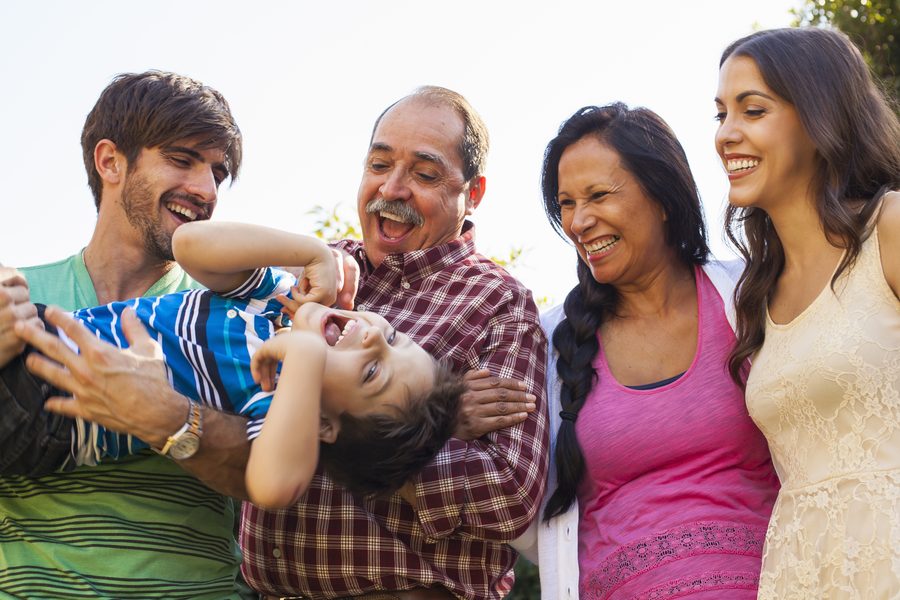 Una famiglia di tre generazioni ride insieme mentre gioca con un bambino